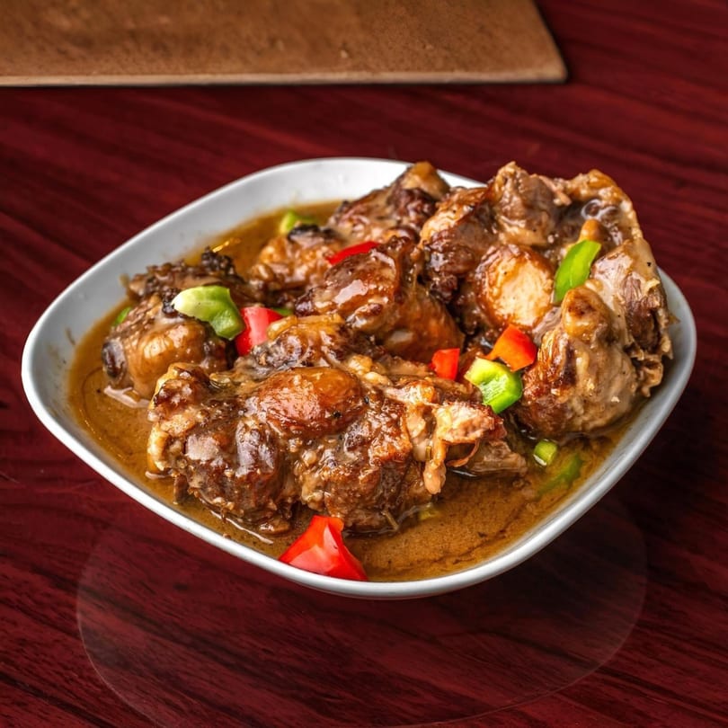 Supreme Seafood & Suya's African oxtail stew, garnished with red and green bell peppers.